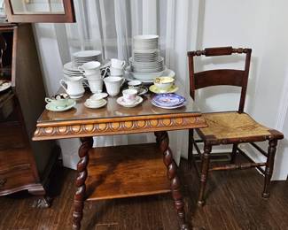 Square tiered mahogany table, cane chair, various cups and saucers, set of china