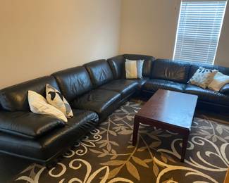 Black leather wrap around sectional couch. Very low to the ground, probably from 1980s.