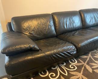 Black leather wrap around sectional couch. Very low to the ground, probably from 1980s.