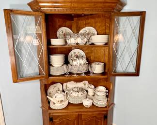 Lighted corner cabinet with china.