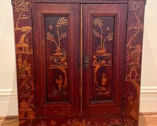 $1500 - Antique, deep red, hand-painted Chinoiserie two-door wooden cabinet. Provenance; purchased from a highly respected antique dealer in New Orleans. There are a few drilled spots on the back indicating it may have been used to hold electronics at one point. 43 x 19 x 46