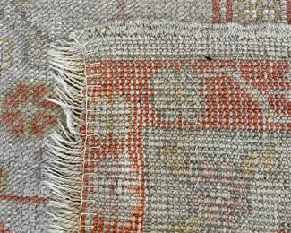 $2000 - 10’ x 13’ (approx); hand-knotted, wool rug with cream background and terracotta accents; close up of the reverse side of the rug