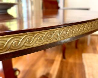 Detailed view of  $3500 - Russian neoclassical mahogany pedestal table wit brass edging and base accents; close up of the metal trip on the edge of the table