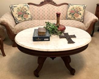 Neatly upholstered antique sofa; antique marble top oval coffee table; décor 