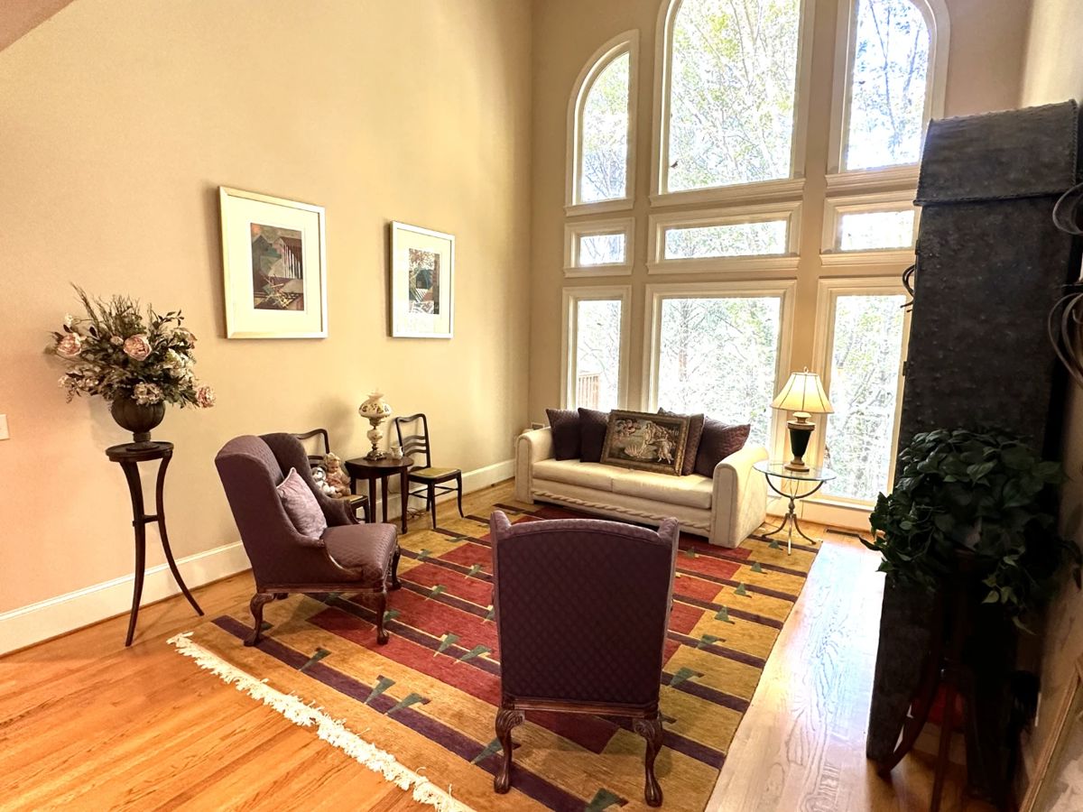 area rugs, silk flower arrangements, antique dining chairs, burgundy armchairs, beige sofa, throw pillows, brass and glass end table, framed wall art, display case, china cabinet