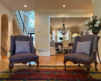 area rugs, silk flower arrangements, antique dining chairs, burgundy armchairs, beige sofa, throw pillows, brass and glass end table, framed wall art, display case, china cabinet