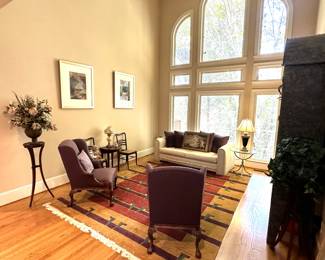 area rugs, silk flower arrangements, antique dining chairs, burgundy armchairs, beige sofa, throw pillows, brass and glass end table, framed wall art, display case, china cabinet