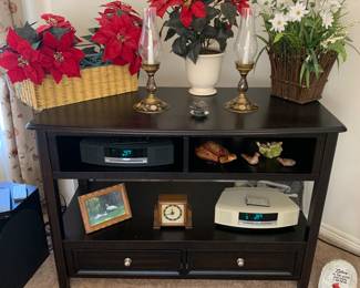 Sleek stand that could be used for a television, as a sofa table, etc.   Multiple Bose radios, vintage clock, flowers