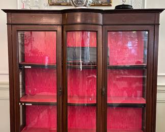 Framed textile above a lighted inlaid-wood vitrine/display cabinet