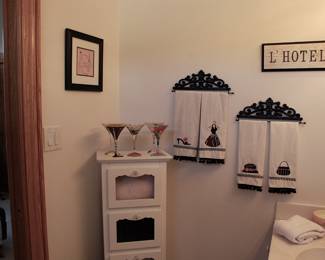 White 5 shelf cabinet with glass door pull down open.  Boutique signs, decorative towels and more.