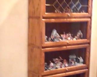 Light oak bookcase with lifting glass closures on each shelf.