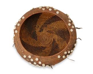 45
A Pomo Gift Basket
Early 20th century; Northern California
A coiled low bowl with central five-armed swirling sawtooth motif, enhanced with applied shell discs, beads, and topknot accents
2.75" H x 7.25" Dia.
Estimate: $500 - $700