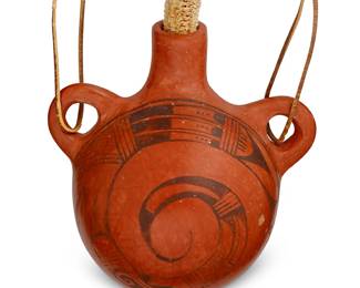 305
Lena "Corn Woman" Charlie (1888-1978, Hopi-Tewa)
A redware canteen, mid-20th century
Signed with artist's corn cipher to underside
The canteen with hide strap tied to opposed lug handles, painted black on red swirling geometric motif, and later added corn cob stopper
8.5" H x 8.25" W x 6" D
Estimate: $200 - $300