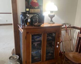 Folk Art painting on board, miscellaneous crocks and churn, oil lamp and shade, vintage sled, pie safe with miscellaneous quilts