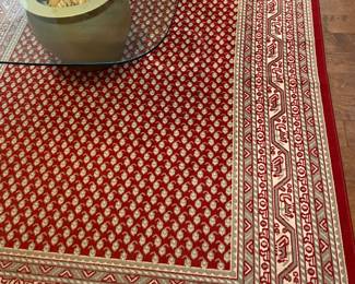 glass coffee table with large shell centerpiece, red and tan area rug