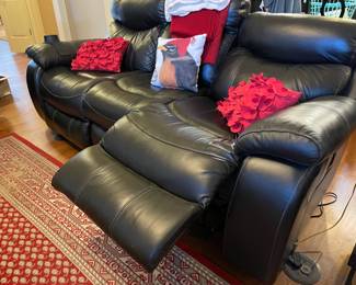 electric black leather recliner sofa, red area rug, red throw pillows