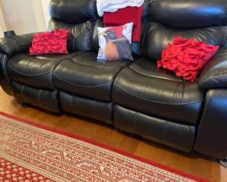 electric black leather recliner sofa, red area rug, red throw pillows