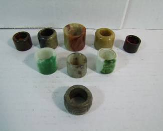 Lot 73:   9 Antique Jade Archers Rings includes 1 with text carving, various colors and sizes.  Tallest is 1 1/4".  Cond: Some have edge wear.   Est. $ 100 - 150.