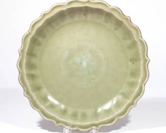 CHINESE LONGQUAN CELADON CHARGER | Ming dynasty (1368-1644), with scalloped, barbed rim, fluted cavetto and lightly impressed floral decoration at center, covered in a thick sea-green glaze except for a ring on the base which is burnt orange from the firing
dia. 11 in.