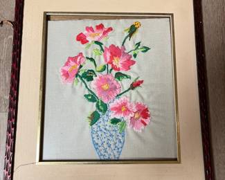 Framed needlework, flowers in vase.