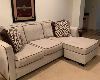 Modern beige fabric sofa with brown trim & pillows.
