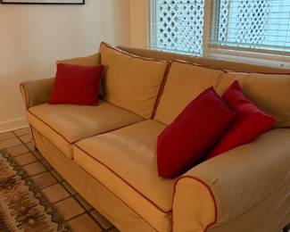 Sofa with beige slip covers and red pillows.  Sofa is red but needs slip cover!