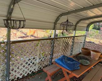 Inside the 2-car carport, picnic table, flower pots, tarp, hanging flower pot