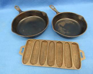 Lot 143. Three pieces of cast iron cookware.&nbsp; 9" and 5" skillets and a cornbread pan