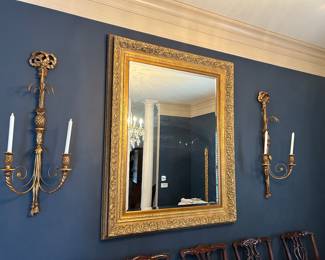 Large gold framed beveled mirror and tall sconces.