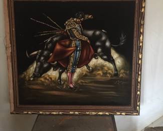 Black velvet provides a dramatic backdrop for a seemingly successful matador. It’s sitting atop an industrial looking cart with drop leaves. 