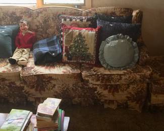 A couch featuring brown flowers on a soothing cream background also has a matching ottoman. 