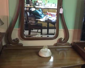 An unusually tall mirror tops a three-drawer dresser, a fitting piece for an entryway or bedroom. 