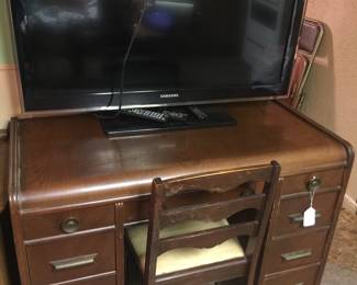 An older wood desk with plenty of drawers for power cords, tablets and many of today’s home office needs comes complete with a coordinated chair. The Samsung flatscreen television, a bit large for this desk, is also available. 
