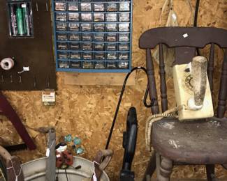 A hanging organizer, old-fashioned planters in a large rolling planter, a weed trimmer. an old wood chair and a rotary-dial phone showcase the big variety of items. 