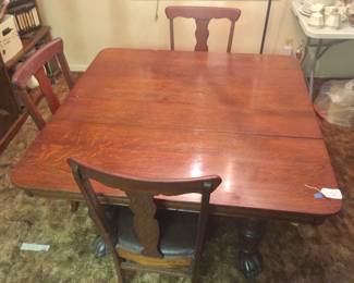An oak dining table with turned legs and claw feet comes with four T-back chairs. 