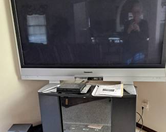 58" Panasonic TV; Classic Home Audio System with 6 CD Changer, AM/FM, Cassette Player; Black Laminate TV Stand with Glass Front Door.