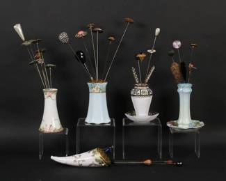 238	35 Vintage Hatpins With Holders	35 hat pins including enamel, rhinestone, cabochon, 1 sterling silver. With 5 porcelain holders including Nippon, RS Germany, Nippon hanging. Hatpin with red and white rhinestones 12"L. Nippon hanging hatpin holder 6 1/2"L. Sterling hatpin 7.3 grams. Line to underside of Nippon holder.
