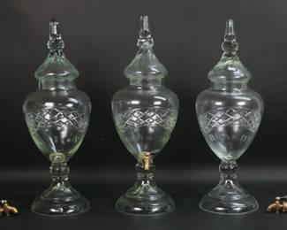 31	3 Glass Apothecary Dispensers	3 cut and etched glass apothecary liquor and root beer dispensers. Root beer, gin and brandy. Each with a lid and brass spigot. Root beer 20 3/4"H including lid. Spigots broken off on Brandy and gin (pieces present) with chips around holes, root beer apparent repair to spigot, flea bites to rims and rims of lids, gin dispenser with chip to rim.
