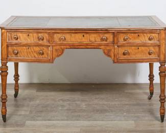 212	Victorian Tiger Maple Writing Desk	"Victorian tiger maple writing desk. Late 19th century. Inset tooled green leather, five drawers, turned legs on later casters. Scratches, marks, wear and losses to leather. Heavy losses to wood on front molded top edge. Warping throughout entirety of desk. Bottom right drawer slightly inset. Splits and cracks to wood on back and left and right sides. Loss to molding on bottom left drawer. Loss to curved molding above front left leg. Splits to bottom panels on all drawers. Chips and losses throughout top edges. Losses to wood on front between drawers.

56 1/2"" W x 27 1/2"" D 32 1/4"" H. 100 lbs."
