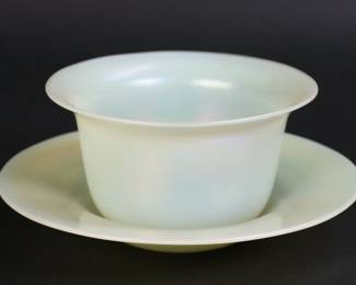 228	Steuben Carder Finger Bowl & Underplate	Frederick Carder for Steuben. Art glass finger bowl and underplate. Iridescent light green / yellow glass. Bowl 2 1/2"H x 4 1/2"-diameter at top, underplate 6 1/4"-diameter. Both signed F. Carder and Steuben around the pontil marks.
