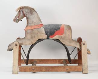 91	Early American Rocking Horse	"Early American rocking horse. Carved wooden horse and stand with leather and felt saddle. Tears and losses to felt. Wear and marks throughout wood of horse and stand. Small cracks to joinery of front legs. Back left leg of stand is warped slightly askew. Tail is separated.

36"" W x 12 3/8"" D x 27 1/4"" H. 10 lbs."
