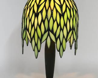 442	L&L WMC Lily Pad Lamp With Tiffany Style Shade	Loevsky & Loevsky white metal lily pad lamp base, with a Tiffany Wisteria style green leaded glass shade. Lamp base signed L&L WMC on the underside. 16 1/2"H including finial, shade 7 1/2"-diameter. Minor losses to patina on top of shade.
