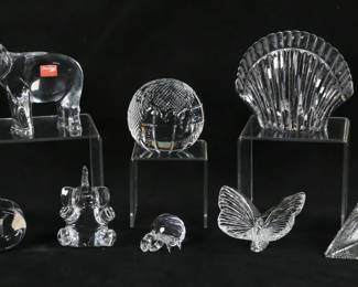136	8 Piece Crystal Lot Steuben, Baccarat, Swarovski	8 piece crystal lot. 4 pieces Waterford: shell paperweight, 4 1/8"H; globe paperweight, 3"H; butterfly, 2"H, Times Square 2000 clock, 3 5/8"H. 3 pieces Baccarat: heart paperweight, 1 1/4"H; 2 elephant figurines, larger 5 1/4"L x 4"H. With a Swarovski crystal crab figurine, 1 1/8"H. Shell paperweight chips and fleabites to top edge and scallops of shell, chips to corners of clock, clock not running.
