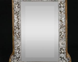 254	English Sterling Dresser Mirror	Hallmarked English sterling silver dresser mirror with easel. Repousse decoration with lions, grapes, figures. English hallmarks, illegible maker's mark, London, circa 1892. 16 5/8" x 11 1/2". Some desilvering to mirror, sterling loose from frame, fraying and tears to velvet lining on frame, small loss to sterling at lower right corner.
