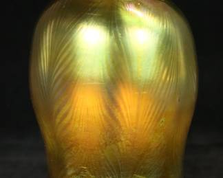 230	Signed Tiffany Favrile Pulled Feather Shade	Tiffany Favrile gold tone iridescent art glass pulled feather shade. Signed on the rim of the fitter L.C.T. Favrile. 3 1/4"-diameter, fitter 2 1/4"-diameter. Chip to the rim above signature, imperfection to the glass on one side.
