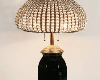 431	LDB & Co. Lamp With Crystal Bead Shade	Black glass table lamp, gilt metal fittings. With a glass beaded shade. Lamp base signed LDB & Co. 26 3/4"H to top of finial. Minor losses to patina on metal.
