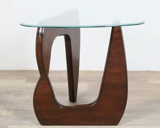 159	Isamu Noguchi Style Side Table	"Side table in the style of Isamu Noguchi (Los Angeles, CA, 1904-1988). Two part hinged wooden base and beveled triangular form glass top. Base separates into two pieces. Small scratches, scuffs, abrasions and wear throughout wood. Small chip and loss to wood on one section of base. Scuffs to edges of glass top. Light scratches, scuffs and wear throughout top of glass. Chips to wood on underside edge of longest part of base.

27 1/8"" W x 26"" D x 24 1/8"" H. 22 lbs."
