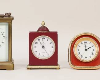 253	4 Travel & Carriage Clocks Including Cartier	Lot of 4 clocks. Duverdry & Bloque French brass carriage clock, 4 3/8"H; Hamilton alarm clock with red enamel, 4 5/8"H; Lexon leather and brass travel alarm clock in leather case, 2 5/8"H; Cartier brass and enamel travel alarm clock, 3"H. Hamilton running, timekeeping untested; D&B, Lexon and Cartier not running. Duverdry & Bloque cracks to front glass upper left corner, cracks and chips to enamel face upper left and right corners; Hamilton losses to red enamel; Lexon losses, wear and fraying to leather on clock and case, wear to brass patina; Cartier minor losses to red enamel, losses and wear to brass patina.
