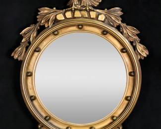 305	Federal Style Bullseye Mirror	"Federal style bullseye mirror. Early 20th century. Carved and gilded wood with eagle crest supporting convex mirror. ""Metropolitan Mirror and Glass"" and ""DEC X 1929"" stamped on back of mirror. Scuffs and wear to mirror. Mirror is loose and separate from frame. Chip and loss to wood on wing of eagle. Chips to acanthus leaves and edges of mirror. One carved leaf is separated but present. 

28 3/4"" x 20 1/2""."
