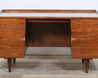 156	Jens Risom Mid Century Modern Desk	"Mid Century Modern desk designed by Jens Risom (Danish-American, 1916-2016). Mid 20th century. Walnut veneer, five drawers, cylindrical dowel legs. Key is included for top right drawer with cylindrical side lock. No apparent maker's marks or labels identified. Scratches, staining, and scuffs throughout wood. Scratches and gouges to wood on top and gallery. Gouges, scratches and losses to wood on left middle and bottom right drawer. Heavy scuffs and marks to wood of feet. 

54"" W x 29"" D x 29 3/4"" H. 144 lbs."
